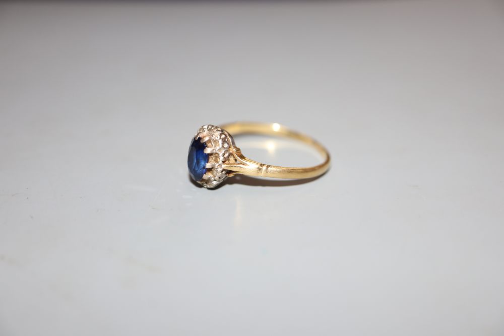 An 18ct, synthetic sapphire and diamond set oval cluster ring, size T, gross 3.2 grams.